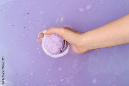 Female hand with dissolving bath bomb in water, closeup