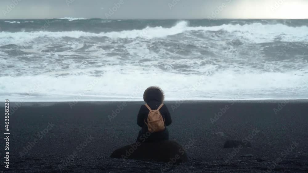 Famous Black Sand Beach In Iceland Slow Motion Person Sitting On A Rock Looking Out At Choppy Waves Crashing
