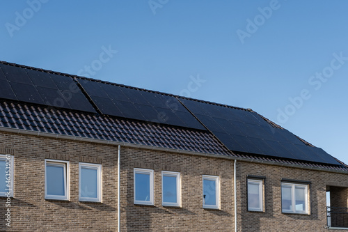 Newly build houses with solar panels attached on the roof against a sunny sky Close up of new building with black solar panels. Zonnepanelen, Zonne energie, Translation: Solar panel, Sun Energy photo