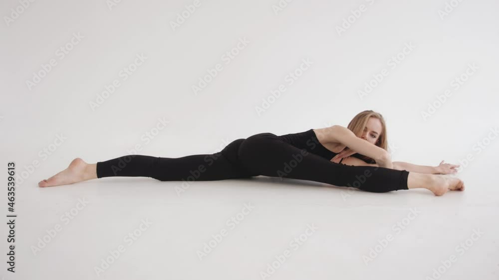 A beautiful young girl is engaged in stretching in the studio and performs a leg raise lying on the floor on her side. A beautiful young girl is engaged in stretching in the studio and performs a leg raise lying on the floor on her side.