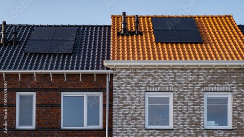 Newly build houses with solar panels attached on the roof against a sunny sky Close up of new building with black solar panels. Zonnepanelen, Zonne energie, Translation: Solar panel, Sun Energy photo