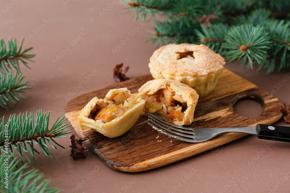 Fototapeta premium Board with tasty mince pies and fork on color background