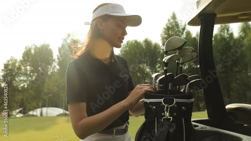 Professional woman golf player choosing the golf club from the bag.