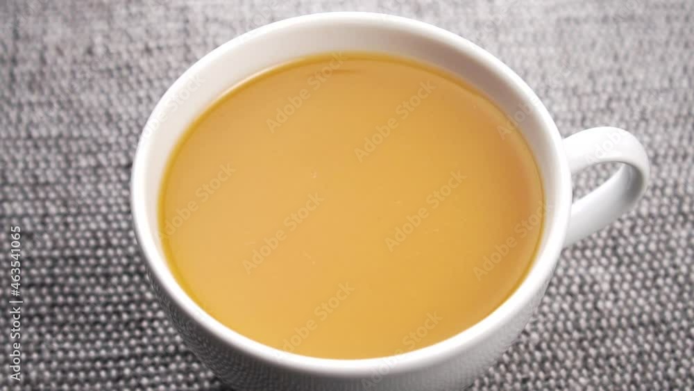 A full white cup of orange fresh squeezed peach juice on a rustic jute fabric. Falling drop in slow motion. Close up. Rotation A full white cup of orange fresh squeezed peach juice on a rustic jute fabric. Falling drop in slow motion. Close up. Rotation