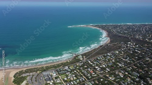Aerial: Gentle waves break on crescent beach leading to rocky point photo