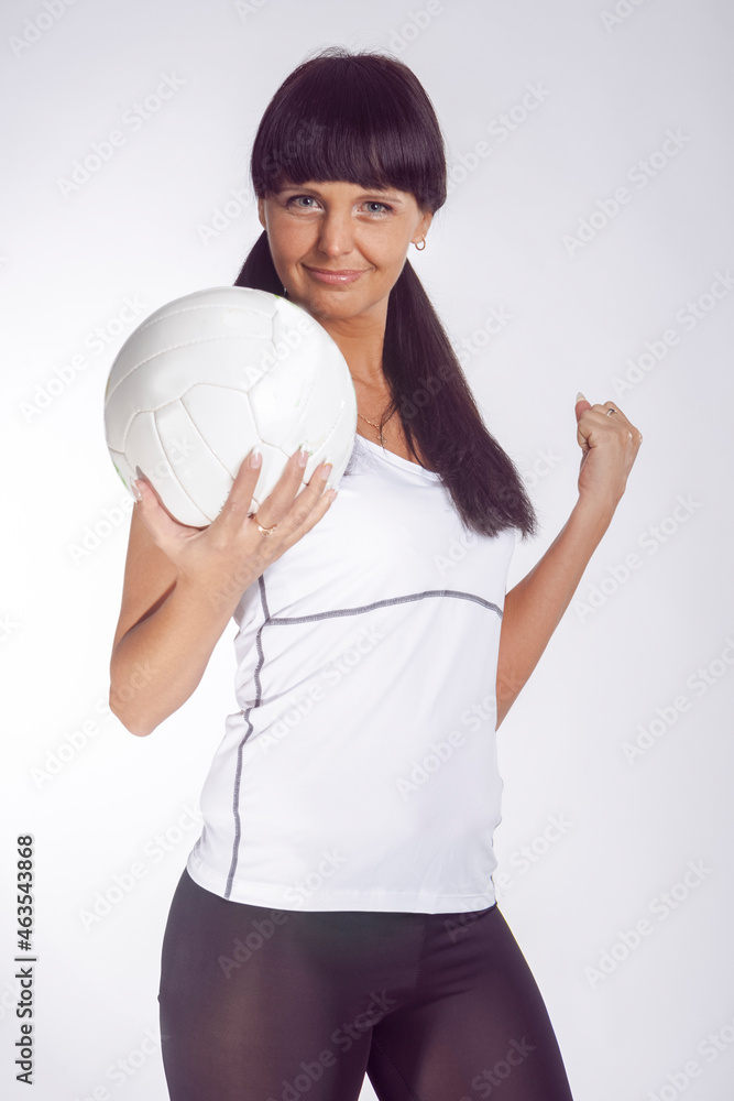 Sport Ideas and Concepts. Portrait of Smiling Caucasian Female Volleyball Athlete During Training Against White Background While Sport Ideas and Concepts. Portrait of Smiling Caucasian Female Volleyball Athlete During Training Against White Background While