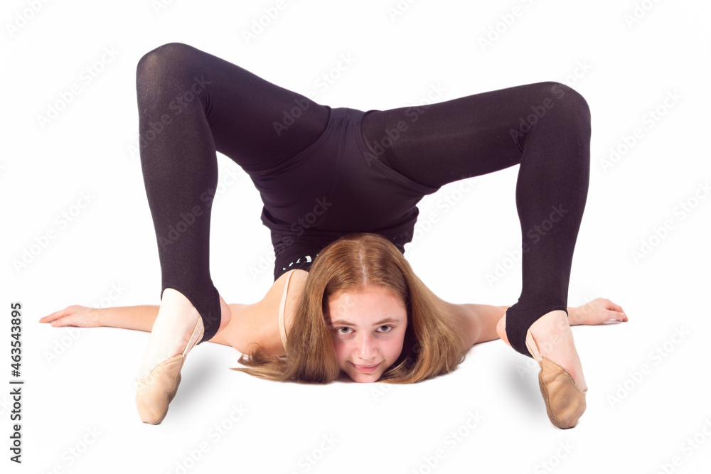 Sport Ideas and Concepts. Young Caucasian Sportswoman Rhythmic Gymnast In Training Black Outfit During Backward Legs Twist Stretching Exercises While Laying on Floor On White. Sport Ideas and Concepts. Young Caucasian Sportswoman Rhythmic Gymnast In Training Black Outfit During Backward Legs Twist Stretching Exercises While Laying on Floor On White.