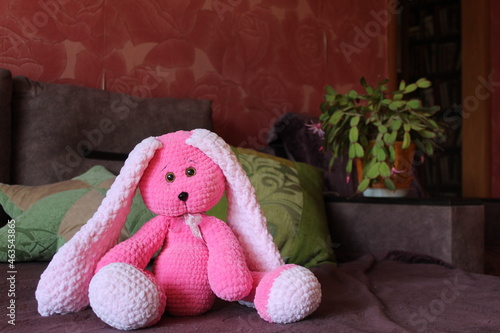 Pink knitted rabbit with a place for text. A toy hare.
