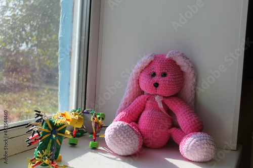 Pink knitted rabbit with a place for text. A toy hare.