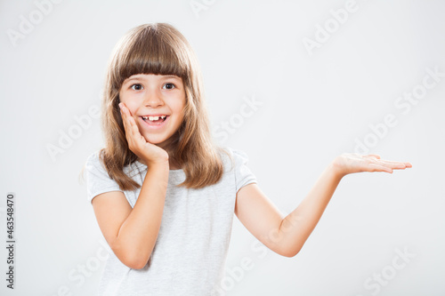 Wallpaper Mural Studio shot portrait of happy little girl holding product or advert on empty copy space on gray background. Torontodigital.ca