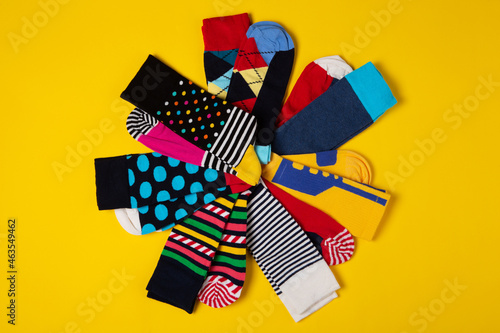 many colored socks with different patterns, laid out radially in the shape of a flower, on a yellow background, concept