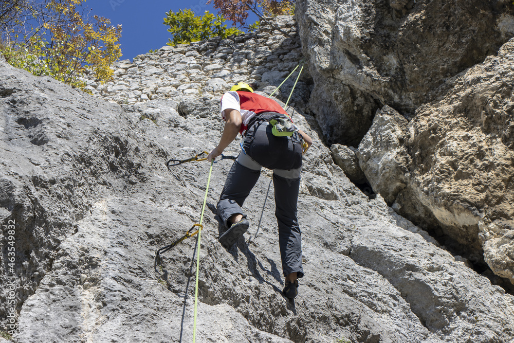 Young man climbing natural high rocky wall
