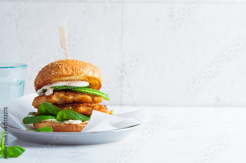 Fish burger on a gray plate. Cod fish in batter with mayonnaise and spinach sandwich. photo
