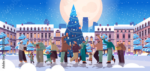 people in santa hats having fun and drinking champagne near decorated christmas tree new year winter holidays celebration