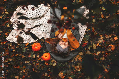 Beautiful little cute girl child happy in autumn in nature lying on a blanket, top view