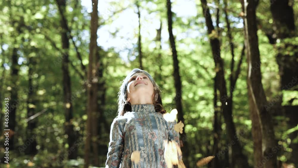 Girl tossing colorful autumn foliage up in air in park. Funny, cheerful cute little girl throwing up a yellow autumn fallen leaves slow motion Girl tossing colorful autumn foliage up in air in park. Funny, cheerful cute little girl throwing up a yellow autumn fallen leaves slow motion