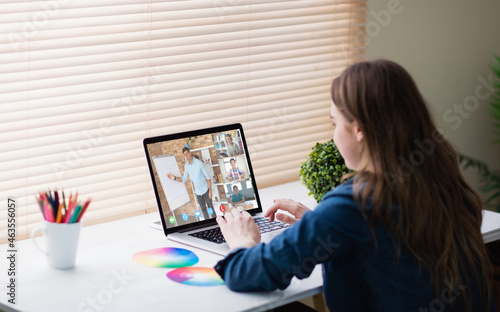 Caucasian girl using laptop for video call, with smiling diverse high school pupils on screen