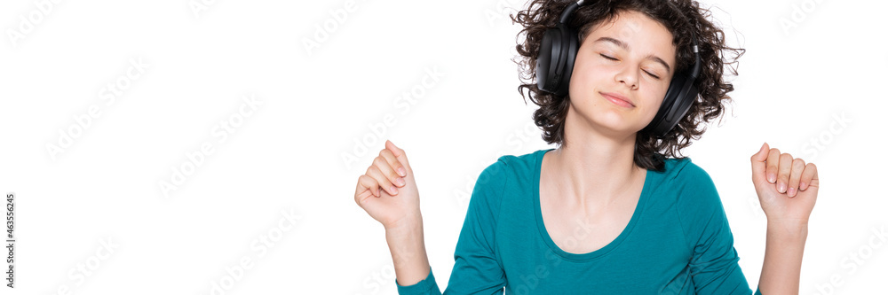 Fototapeta premium Young teenage girl wearing headphones listening and dancing to music isolated over white background. Happy girl enjoying a good song. Music concept.