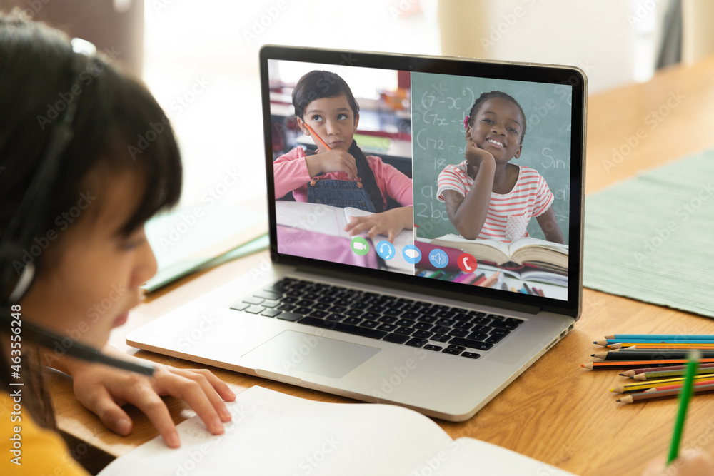 Asian girl using laptop for video call, with smiling diverse elementary school pupils on screen Asian girl using laptop for video call, with smiling diverse elementary school pupils on screen