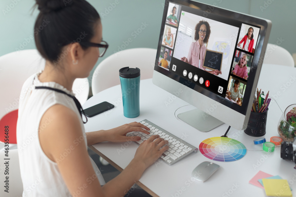Asian girl using laptop for video call, with smiling diverse elementary school pupils on screen Asian girl using laptop for video call, with smiling diverse elementary school pupils on screen