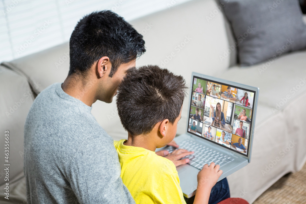 Obraz premium Biracial boy with father using laptop for video call, with elementary school pupils on screen