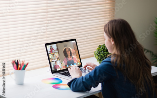 Caucasian girl using laptop for video call, with smiling diverse high school pupils on screen