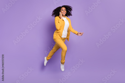 Photo of cute sweet lady wear yellow suit glasses smiling talking modern gadget jumping isolated purple color background