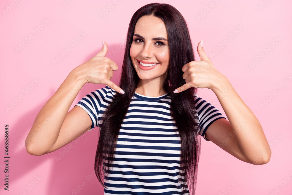 Photo of cheerful nice pretty young woman make call me back gesture line isolated on pastel pink color background Photo of cheerful nice pretty young woman make call me back gesture line isolated on pastel pink color background