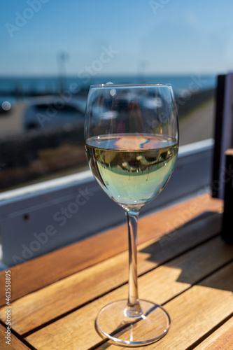 Glass of white wine served on outdoor terrase with seaview  summer vacation