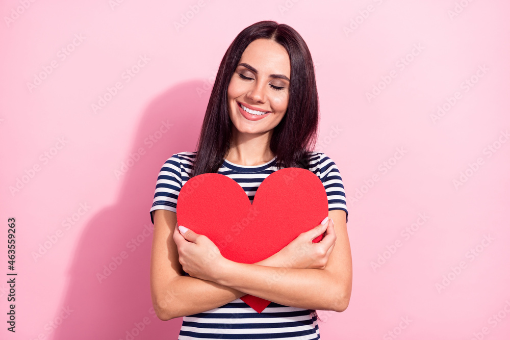 Portrait of attractive dreamy cheerful girl hugging heart shape form figure isolated over pink pastel color background Portrait of attractive dreamy cheerful girl hugging heart shape form figure isolated over pink pastel color background