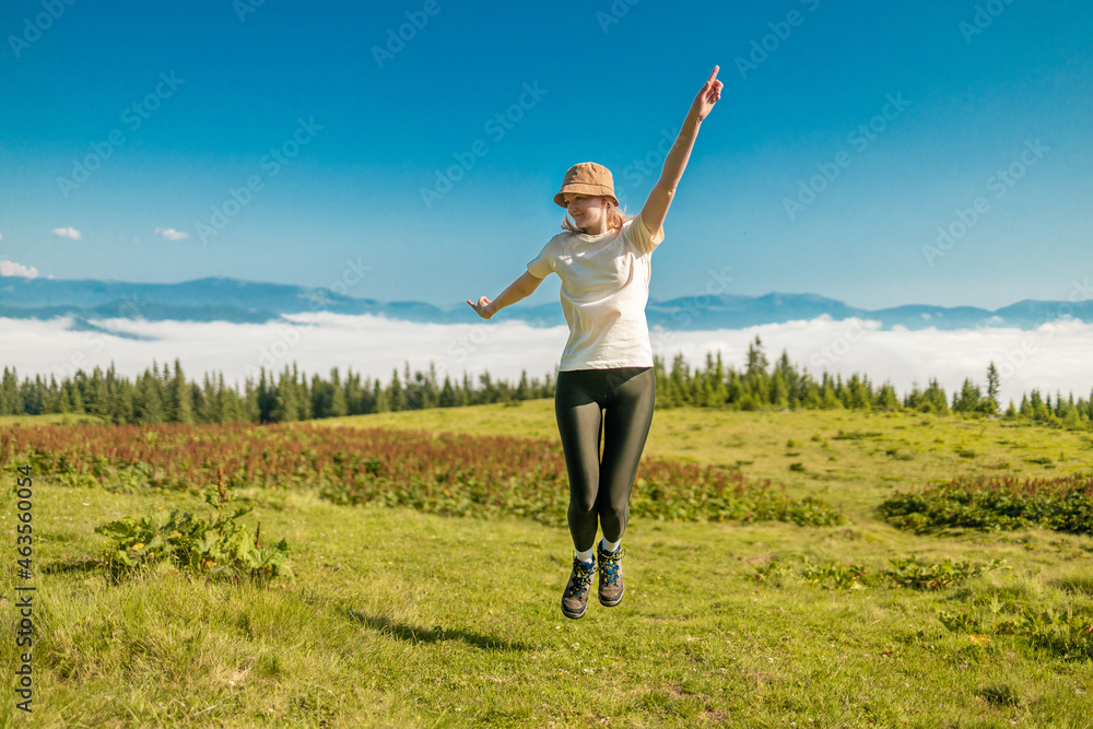 Female tourist jumping up in the nature. Amazing Carpathians landscape background banner with hills, clouds and forest at dawn. Female tourist jumping up in the nature. Amazing Carpathians landscape background banner with hills, clouds and forest at dawn.