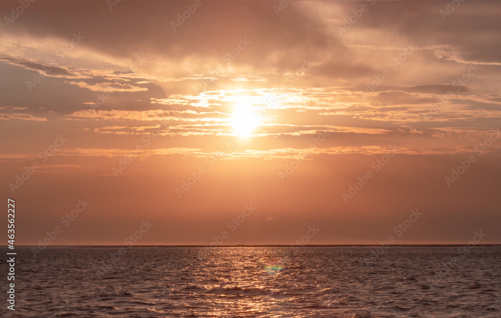 Colorful red sunset and bright sun on the horizon of the ocean beach.