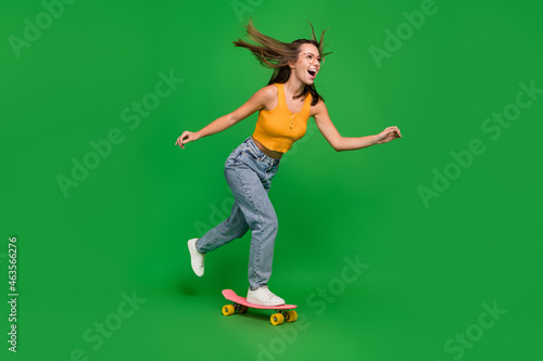 Full body photo of millennial funny brunette lady go wear top jeans shoes isolated on green background