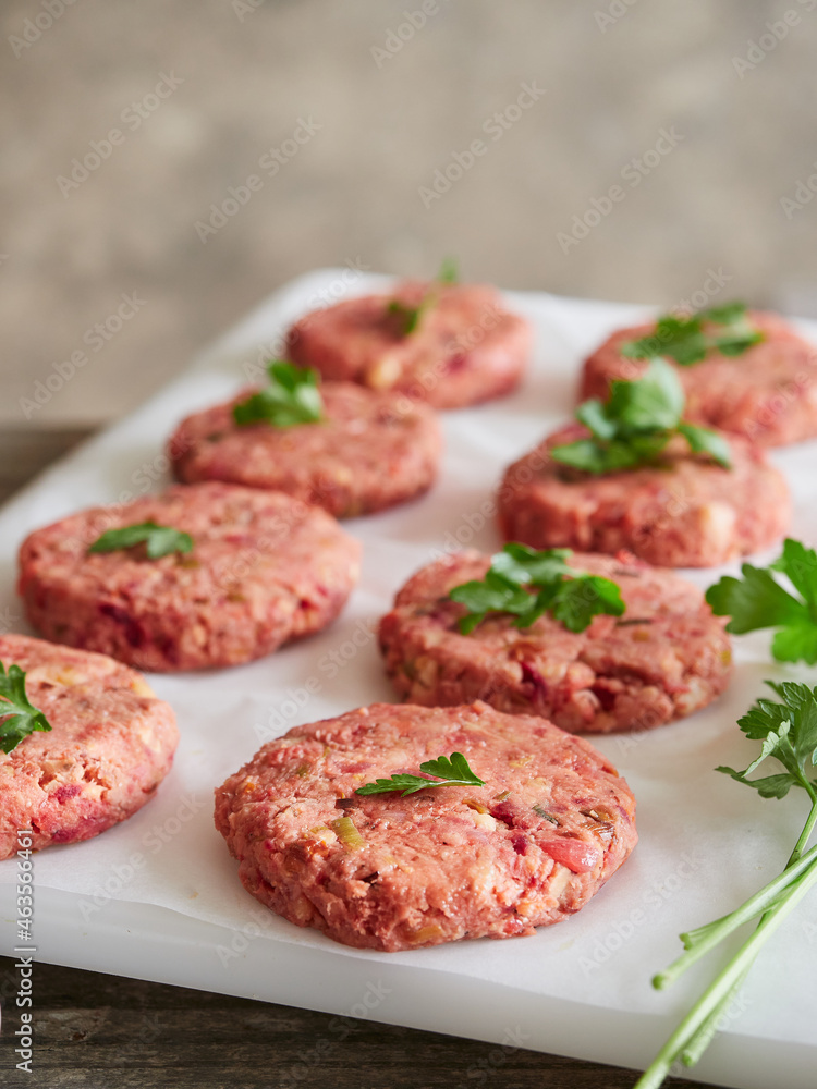 uncooked homemade vegan burger patties placed on white parchment paper with parsley on top. Meat alternative. uncooked homemade vegan burger patties placed on white parchment paper with parsley on top. Meat alternative.