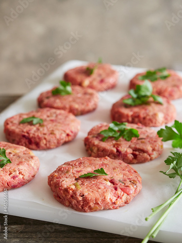 uncooked homemade vegan burger patties placed on white parchment paper with parsley on top. Meat alternative.