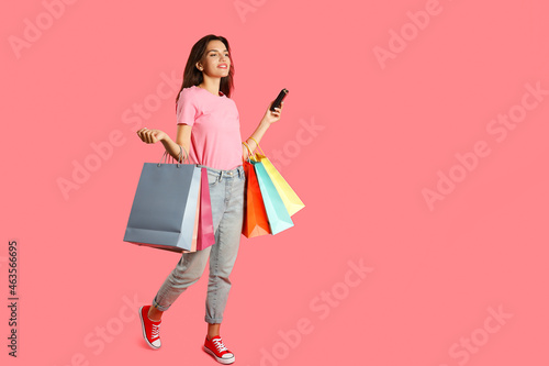 Attractive girl with multicolored paper bags on pink background