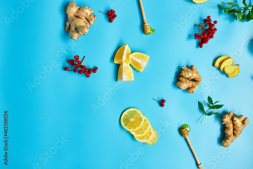 Flat lay of Immune boosting remedy, immunity boosting foods ginger, lemon,  honey,  guelder rose, mint on blue background Top view, copy space. photo