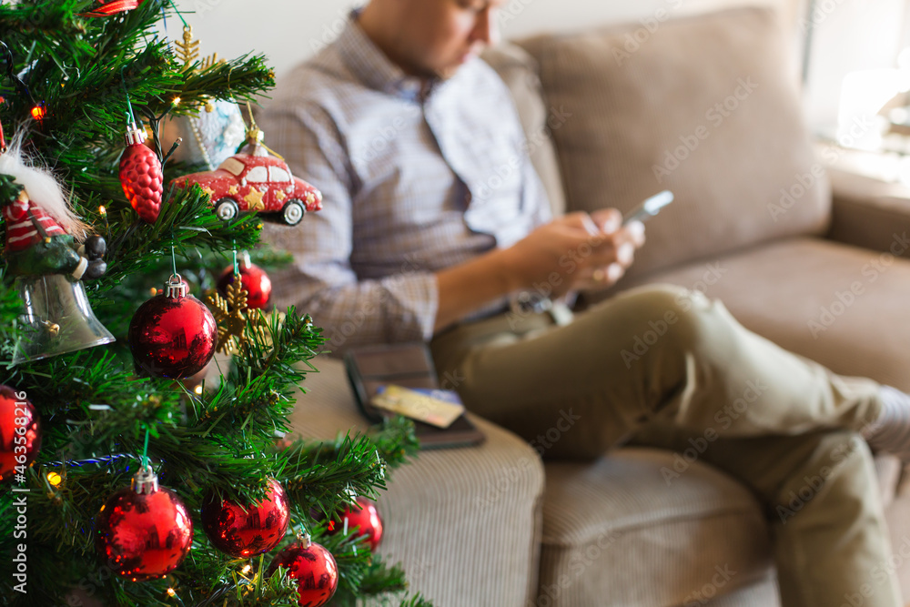 Man buying Christmas, New Year gifts online using phone, laptop