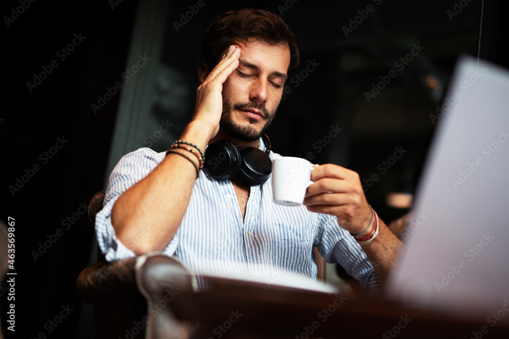 Businessman working on laptop and sitting in cafe. Young man having headache Businessman working on laptop and sitting in cafe. Young man having headache