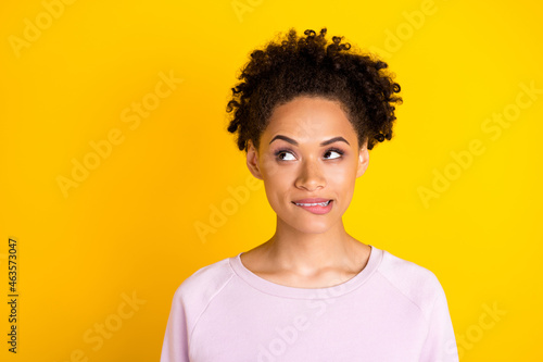 Photo of young dark skin curious woman look empty space minded bite teeth lips isolated on yellow color background © deagreez