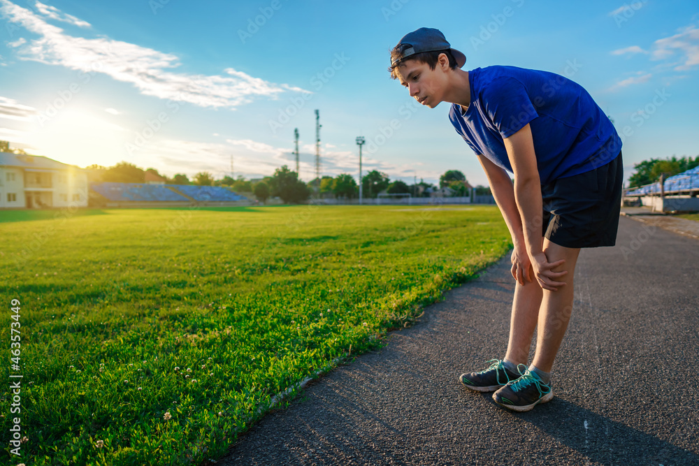 teen boy boy does physical exercises at the stadium track, a soccer field with green grass - concept of sports and health teen boy boy does physical exercises at the stadium track, a soccer field with green grass - concept of sports and health