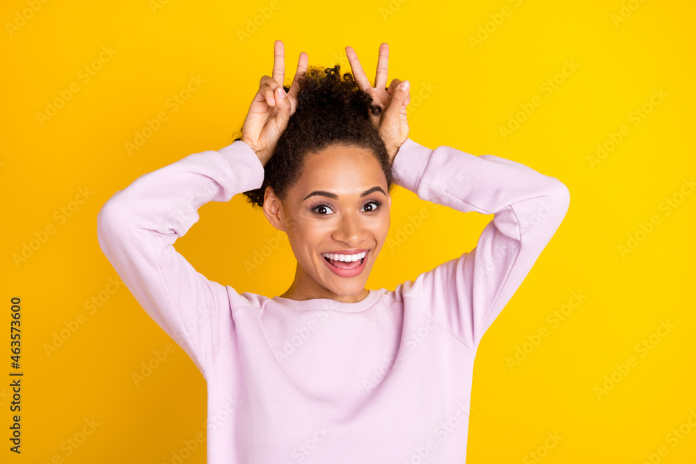 Photo of young happy funky afro american woman hold hands head v-sings isolated on yellow color background Photo of young happy funky afro american woman hold hands head v-sings isolated on yellow color background