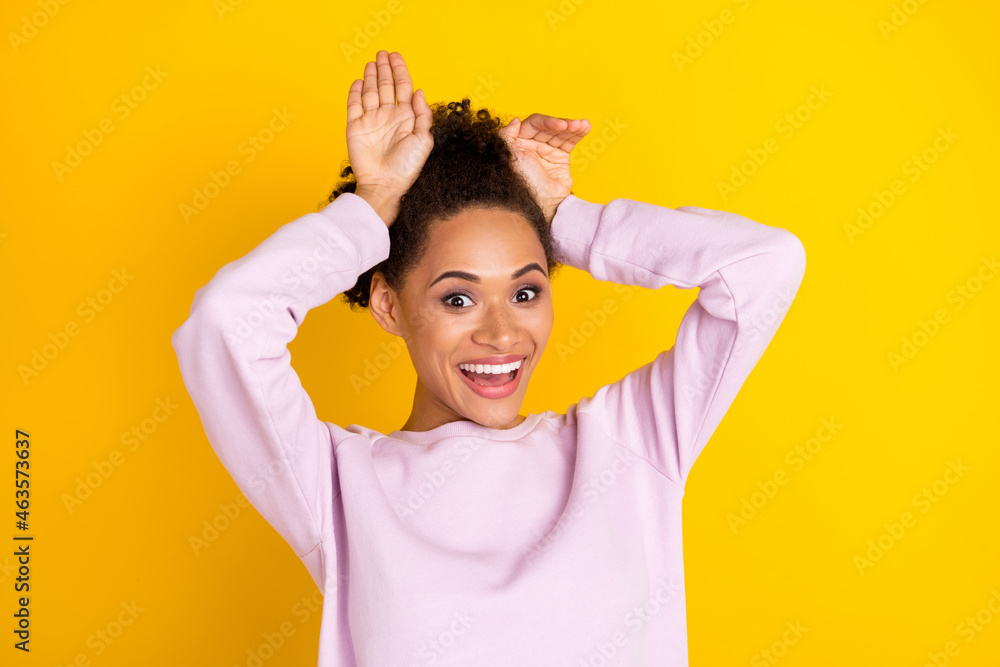 Photo of young happy positive afro american funky girl hold hands bunny ears isolated on yellow color background Photo of young happy positive afro american funky girl hold hands bunny ears isolated on yellow color background