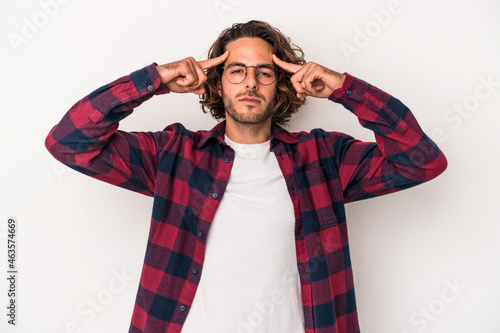 Young caucasian man isolated on white background focused on a task, keeping forefingers pointing head.