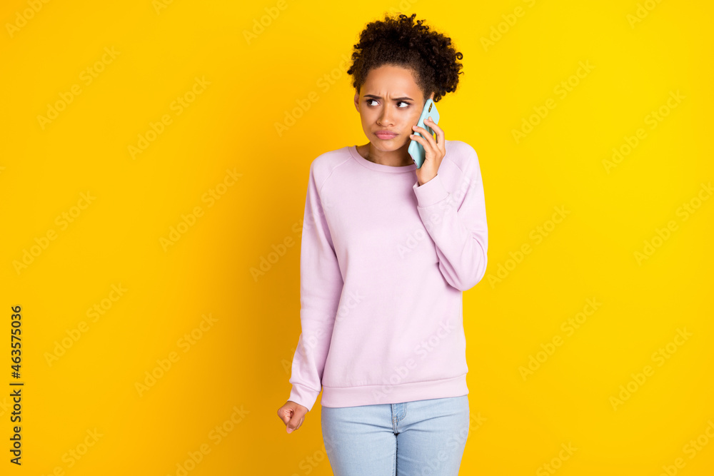 Photo of charming unsatisfied dark skin person speak telephone hear bad news isolated on yellow color background Photo of charming unsatisfied dark skin person speak telephone hear bad news isolated on yellow color background
