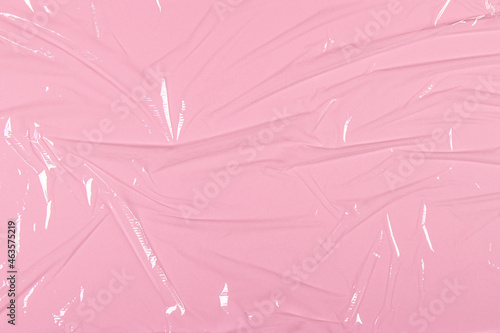Fotografi Crumpled wrinkled plastic transparent plastic cellophane on light pink color background