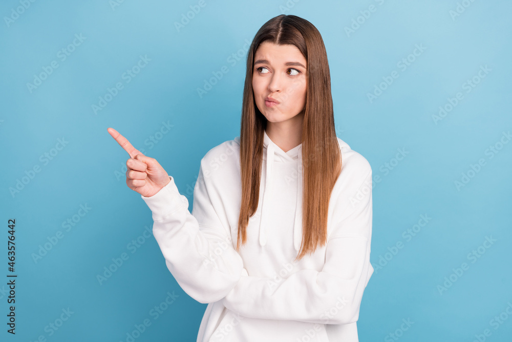 Photo portrait girl pointing empty space unsure in white clothes isolated pastel blue color background Photo portrait girl pointing empty space unsure in white clothes isolated pastel blue color background