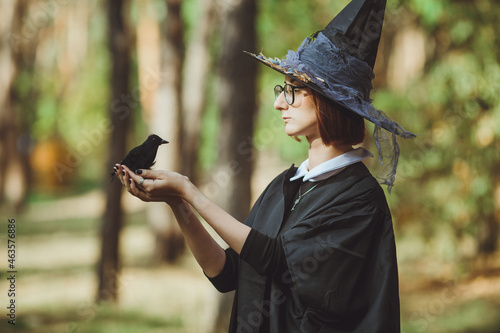 Obraz na płótnie Halloween witch. Portrait of a girl in a hat and witch costume and with a black raven in the forest. Ready for the holiday wallet or life
w salonie
