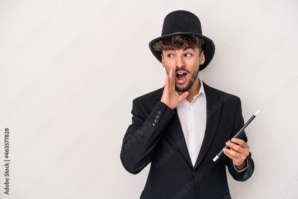 Young arab wizard man holding a wand isolated on white background is saying a secret hot braking news and looking aside Young arab wizard man holding a wand isolated on white background is saying a secret hot braking news and looking aside