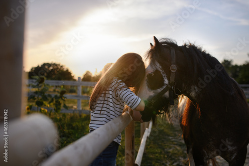 Little girl hugging horse outdoors at community farm.